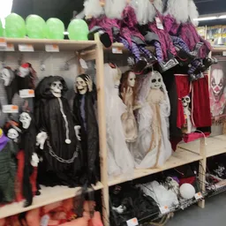Uitgestalde Halloween- en griezelversiering met skeletpoppen en zwarte capes op een winkelrek