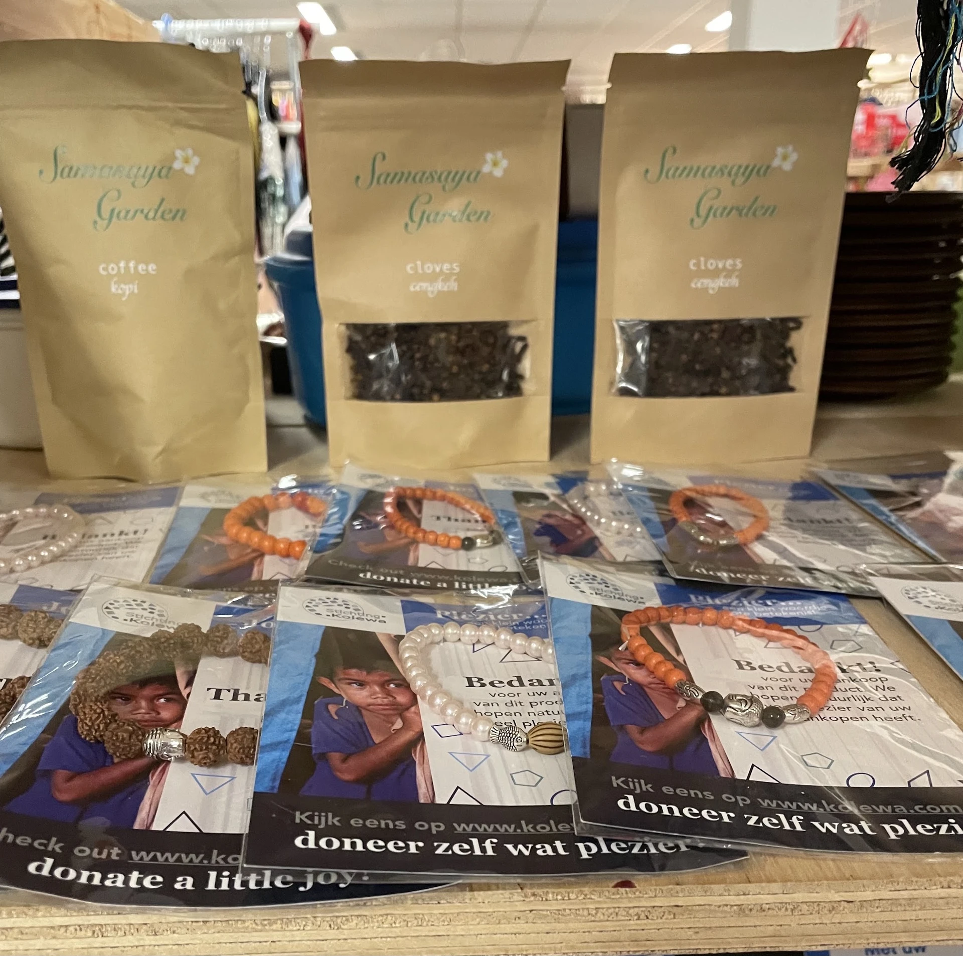 Uitgestalde producten: verpakkingen van Samasaya Garden (koffie en kruidnagel) en armbanden met informatiekaarten