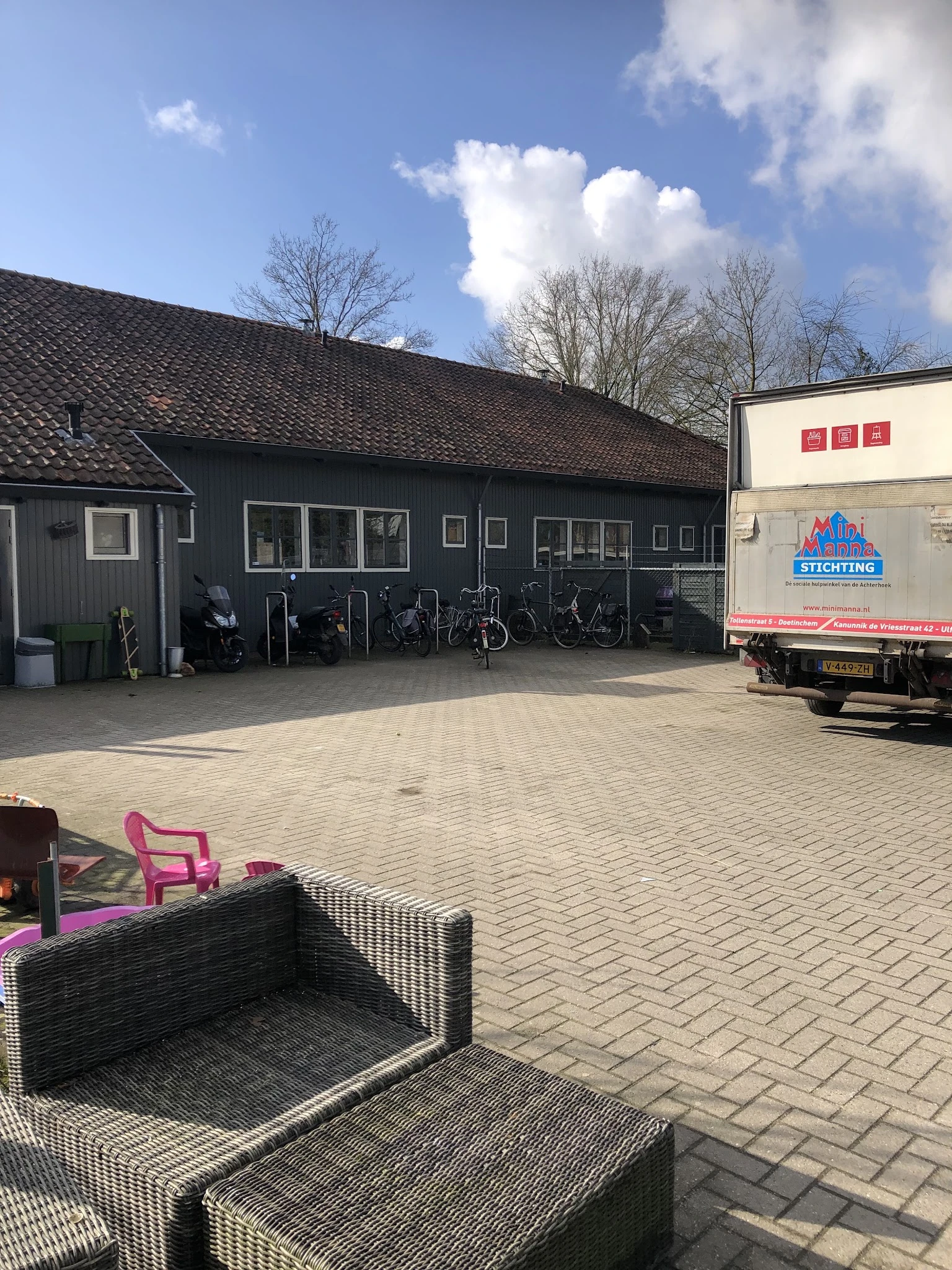 Donkergrijs pand met parkeerplaats vol fietsen en een vrachtwagen ernaast