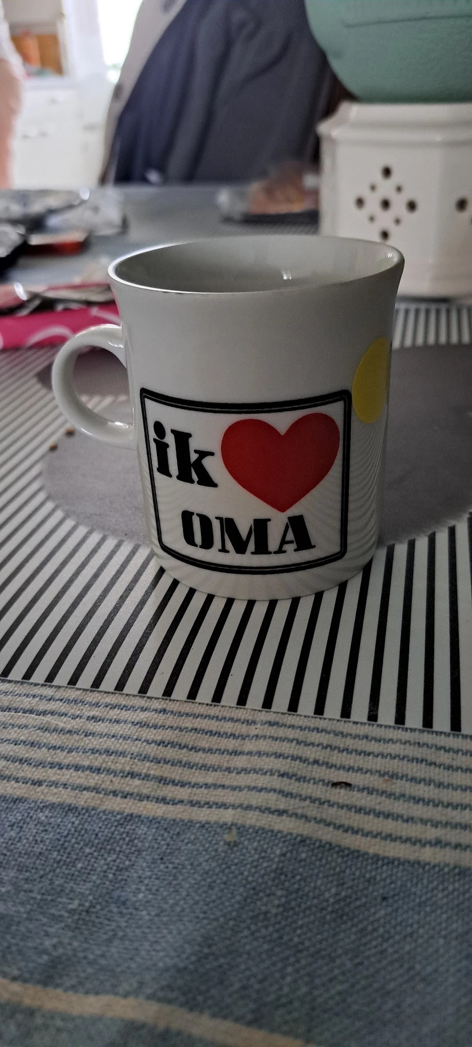 Witte mok met opdruk 'ik hou van OMA' en rood hart op gestreepte ondergrond