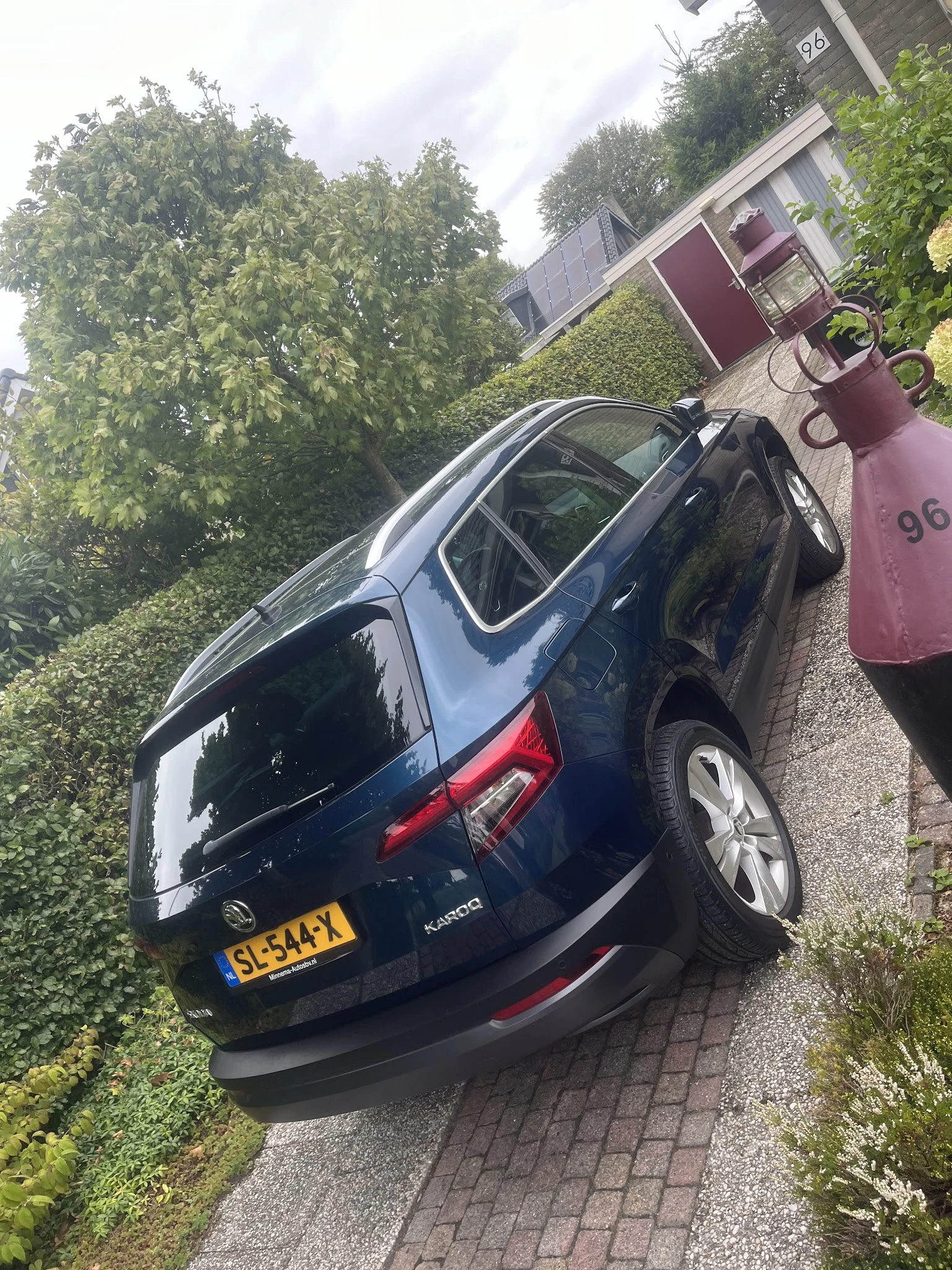 Donkerblauwe Kia-auto van boven gezien op parkeerplaats naast gebouw met klimop