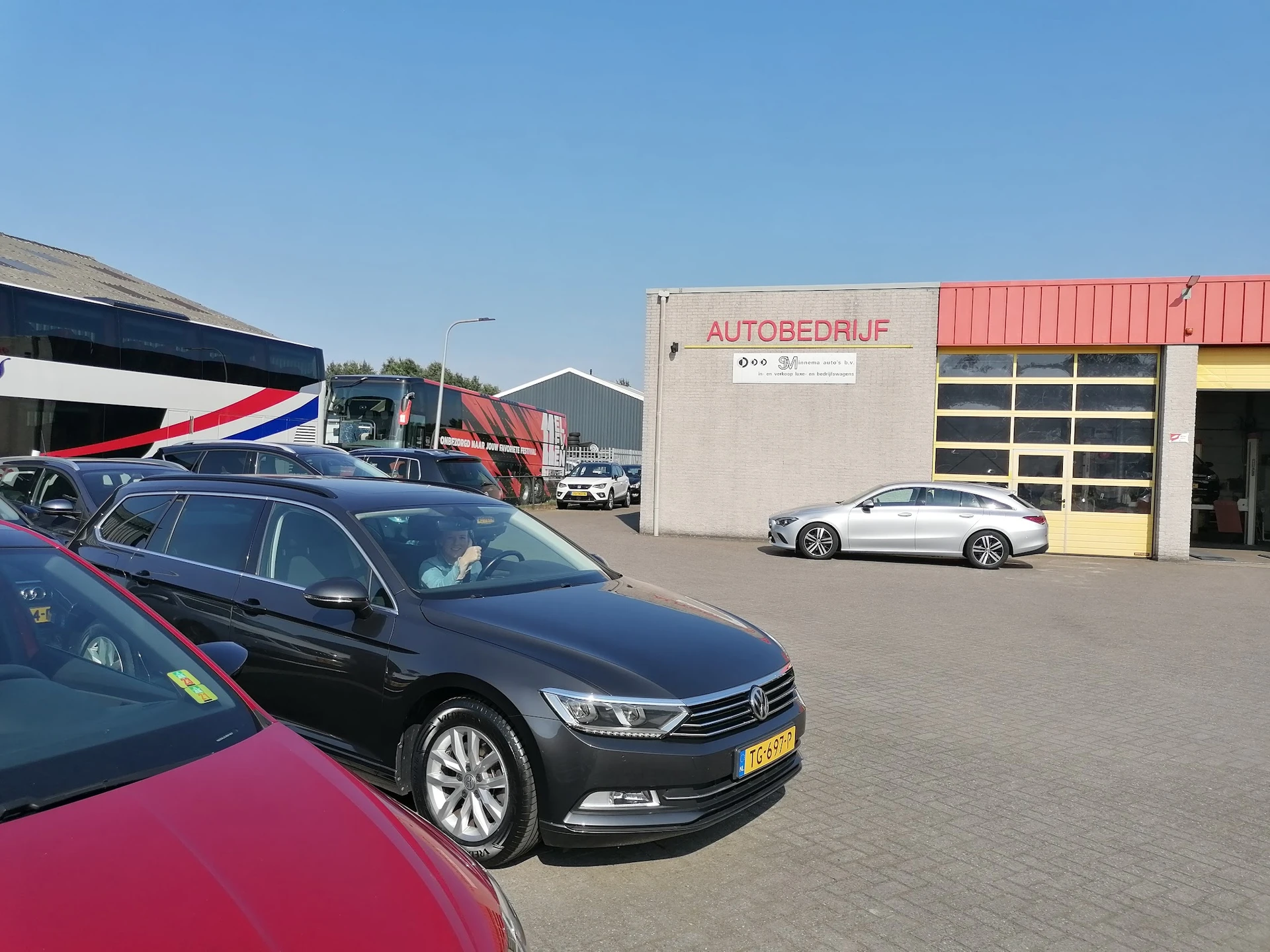 Tweedehands auto's geparkeerd op het terrein van een autobedrijf, met een donkerblauwe sedan op de voorgrond