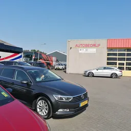 Tweedehands auto's geparkeerd op het terrein van een autobedrijf, met een donkerblauwe sedan op de voorgrond