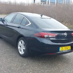 Zwarte Opel Insignia sedan op parkeerterrein, zijkant zichtbaar met kentekenplaat