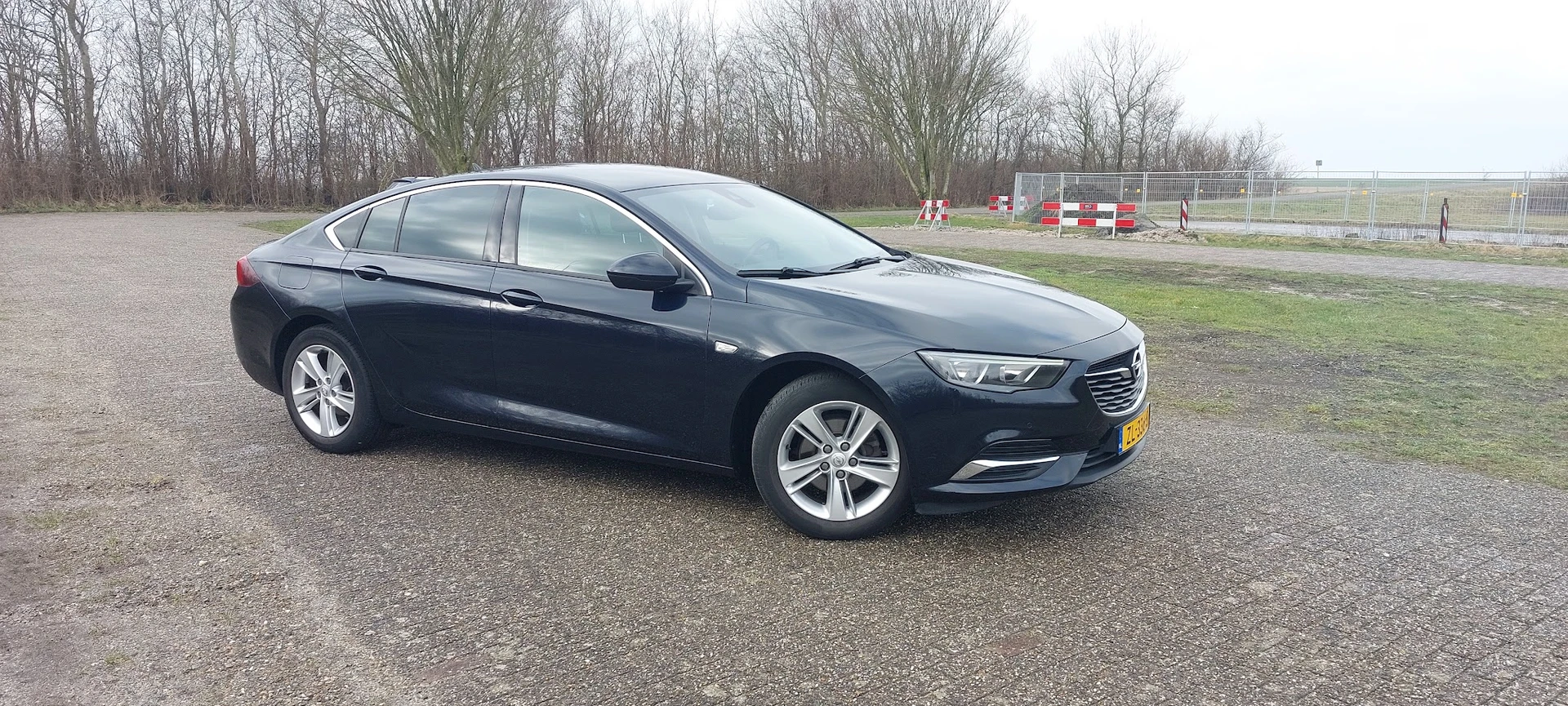 Donkerblauwe Opel Insignia Sports Tourer op een parkeerplaats, zijkant zichtbaar
