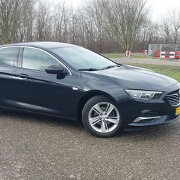 Donkerblauwe Opel Insignia Sports Tourer op een parkeerplaats, zijkant zichtbaar