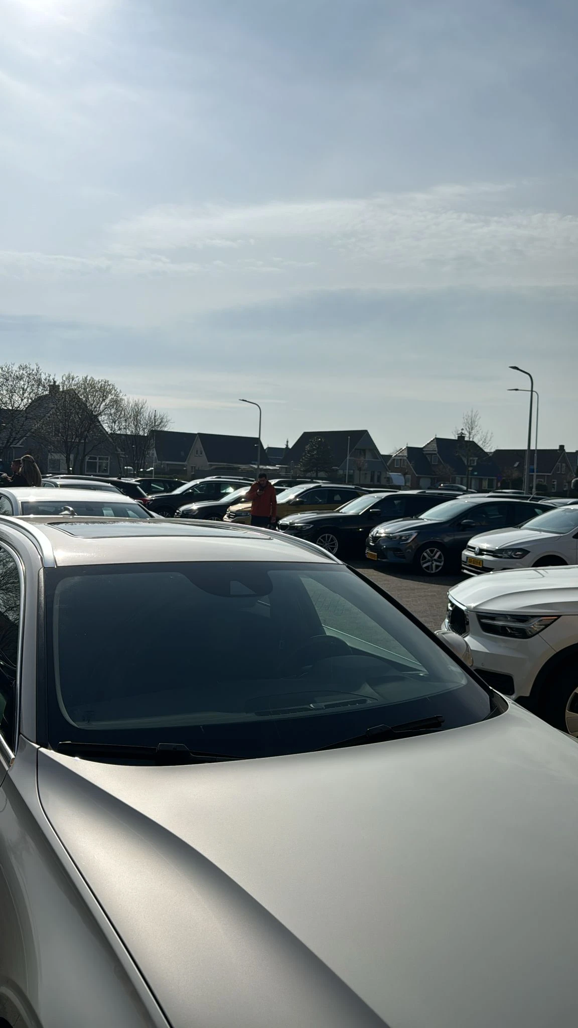 Parkeerplaats met meerdere tweedehands auto's te koop, huizen op achtergrond