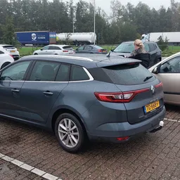 Tweedehands Renault Mégane Estate in blauwe kleur op het parkeerterrein tussen andere auto's