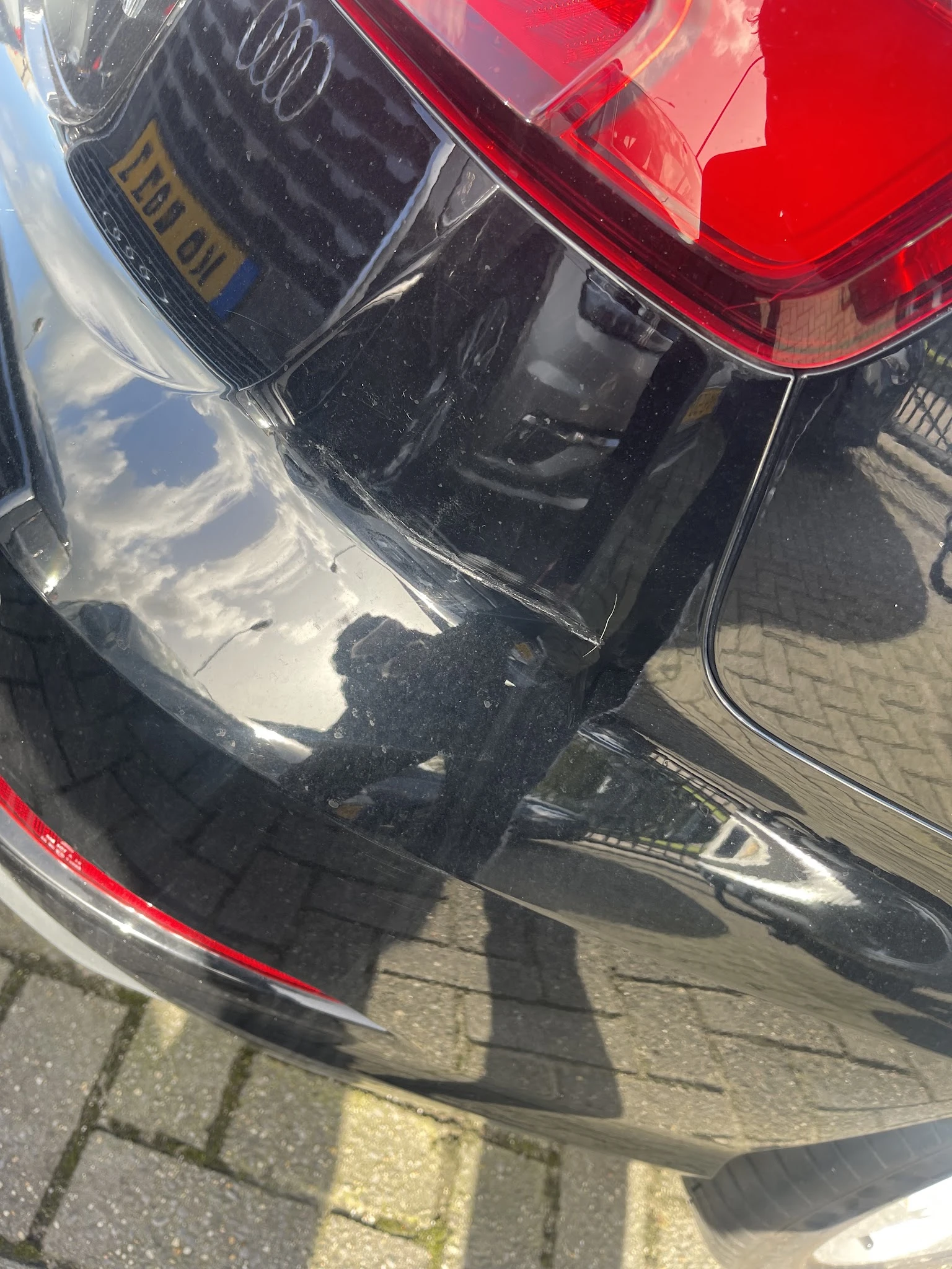 Bovenaanzicht van zwarte auto met spiegeling en schaduw op parkeerplaats