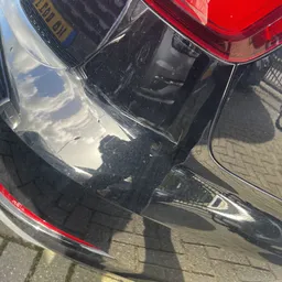 Bovenaanzicht van zwarte auto met spiegeling en schaduw op parkeerplaats