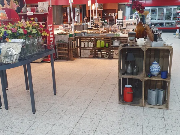 Winkelvloer met bruine houten meubels, decoratieve items in rekken en bloemen op tafel links