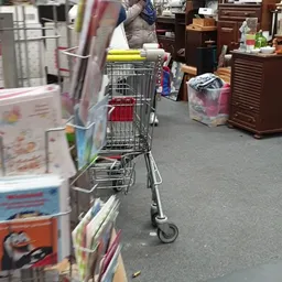 Winkelwagen en dozen met spullen op de vloer van een kringloopwinkel