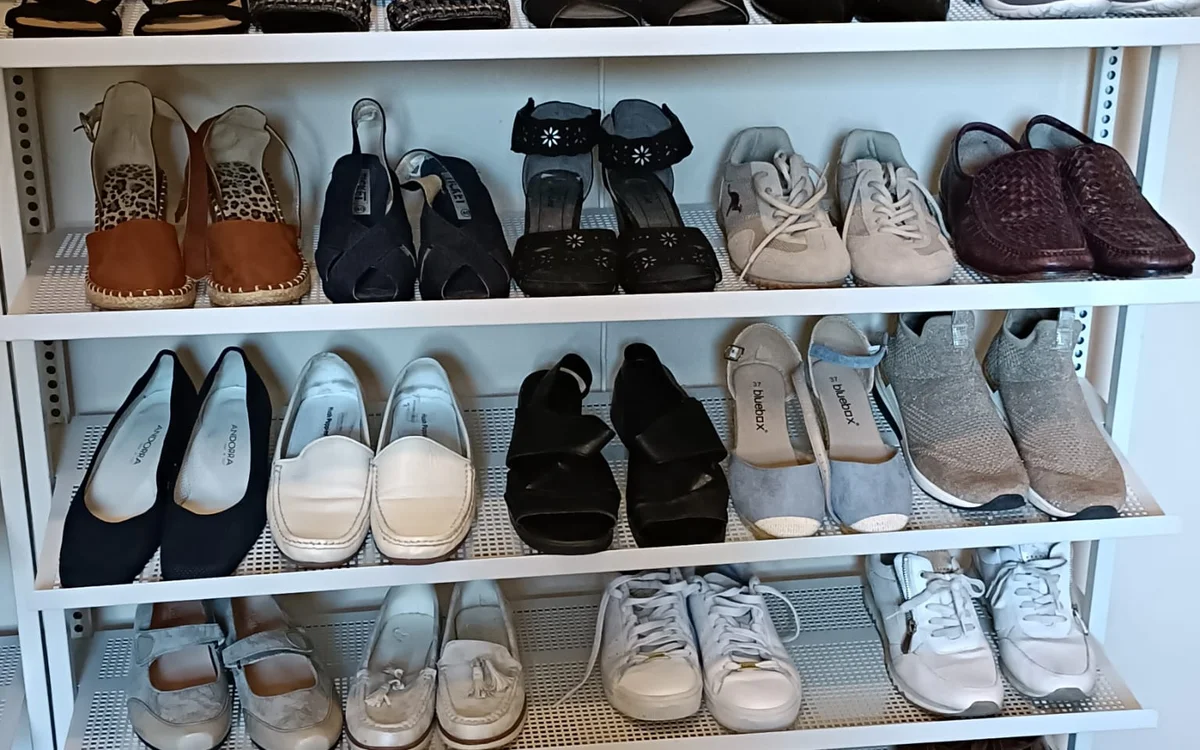 Witte winkelkast met schoenen op meerdere niveaus, waaronder laarzen, sneakers, pumps en pantoffels
