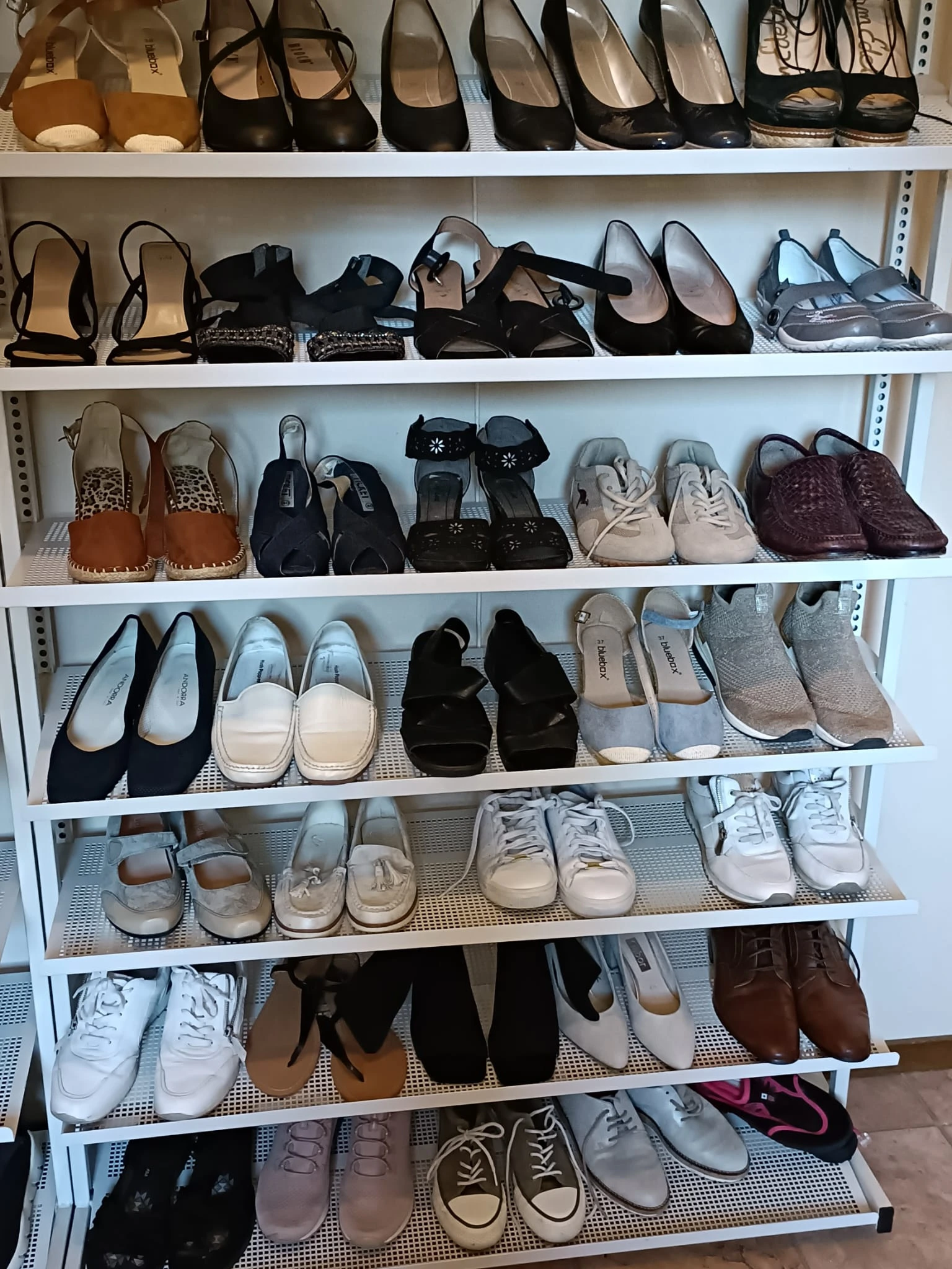 Witte winkelkast met schoenen op meerdere niveaus, waaronder laarzen, sneakers, pumps en pantoffels