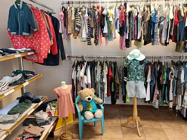 Tweedehands kinderkleding en speelgoed in een kringloopwinkel met rekken, stellingen enDisplayItems