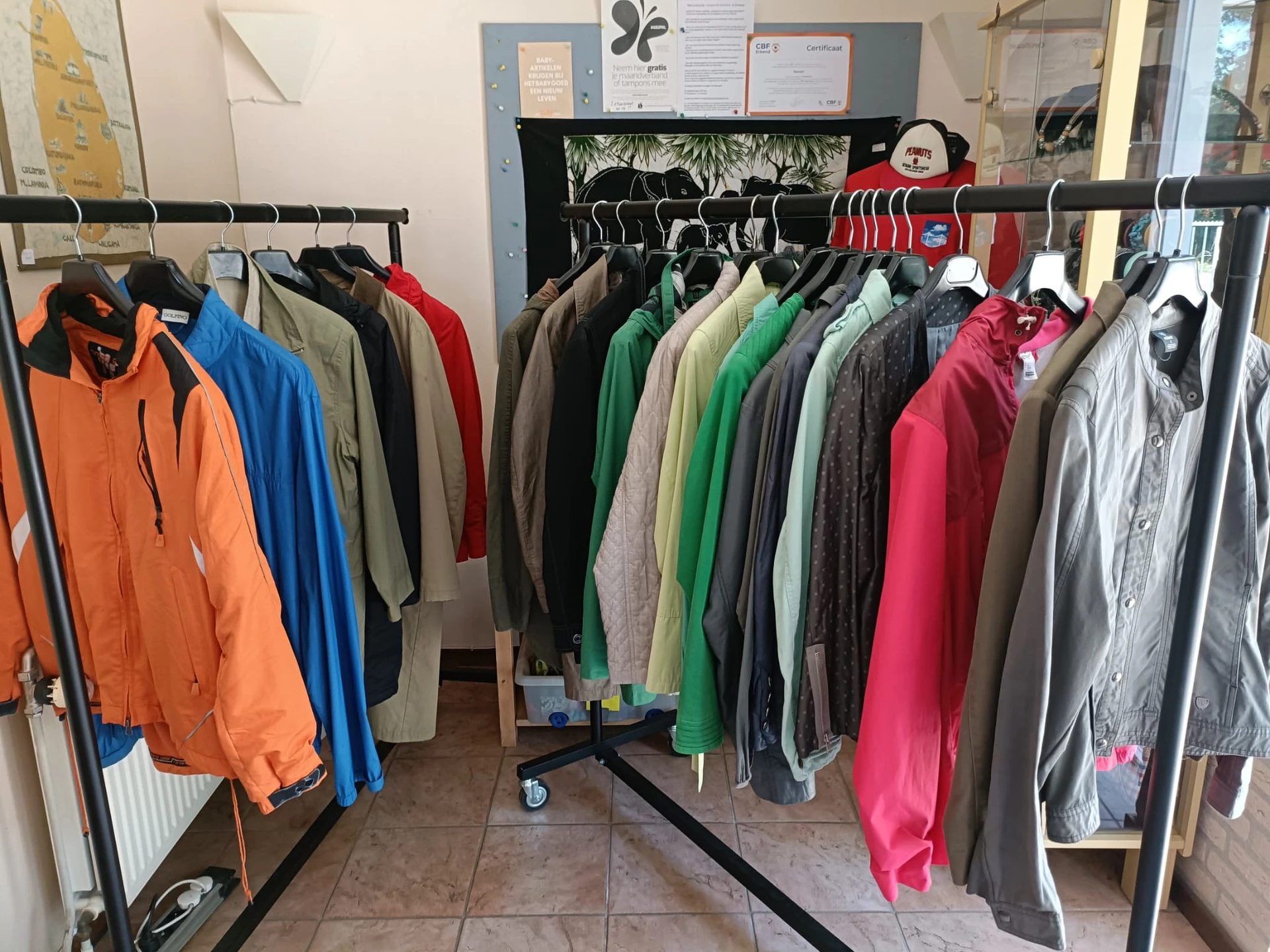 Rekken met tweedehands jassen en jacks in verschillende kleuren, georganiseerd per kleur