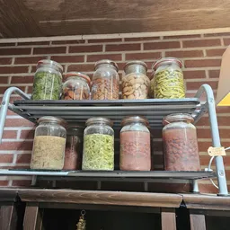 Twee schappen met glazen potten gevuld met verschillende gedroogde voedingsmiddelen en kruiden