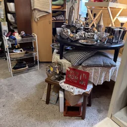 Winkelinterieur met zwarte ronde tafel, kussens, witte stellage en diversen spullen