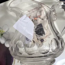 Glazen pot met inhoud en wit etiket, tegen licht gefotografeerd
