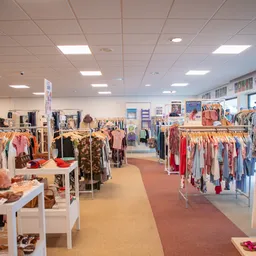 Winkelvloer met rekken vol tweedehands kleding, verschillende kleuren en stijlen uitgestald