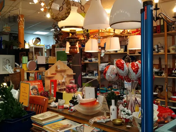 Winkelbinnenkant met stellingen vol lampen, servies, boeken en diverse huishoudelijke spullen