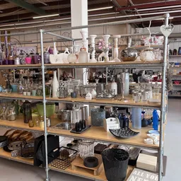 Industriële stellingen vol met huishoudelijke artikelen, glaswerk, decoratie en keukengerei