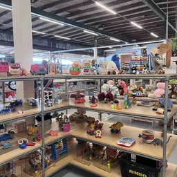 Uitgestalde speelgoed en knuffels op metalen stellingen in verschillende niveaus