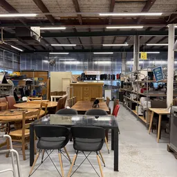 Ruim winkeletalage met meubels, tafels, stoelen en kasten in een kringloopwinkel