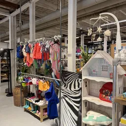 Winkelvloer met kledingrekken, speelgoed en meubels in een kringloopwinkel