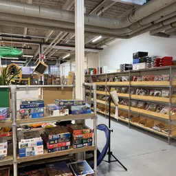 Stellingen met dvd's, blu-rays en spelletjes, en tafels met bordspellen en andere tweedehands artikelen