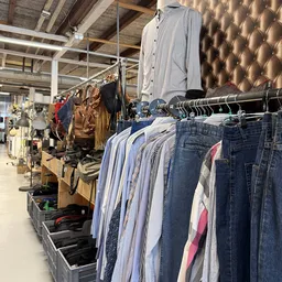 Rekken met tweedehands kleding: jassen, hemden en jeans uitgestald in de winkel