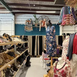 Interieur van kringloopwinkel met schoenrekken, kledingrekken en uitgestalde kleding
