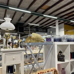 Uitgestalde huisraad en decoratieartikelen op een display in de kringloopwinkel, waaronder gouden decoratieve objecten en div