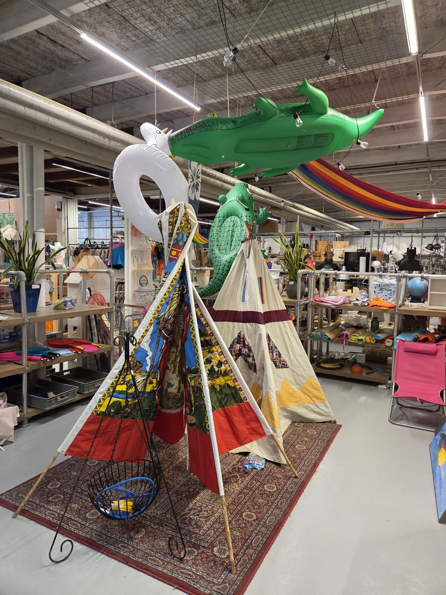 Kleurrijke tipi tent en groene decoratieve items uitgestald in een kringloopwinkel