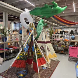 Kleurrijke tipi tent en groene decoratieve items uitgestald in een kringloopwinkel
