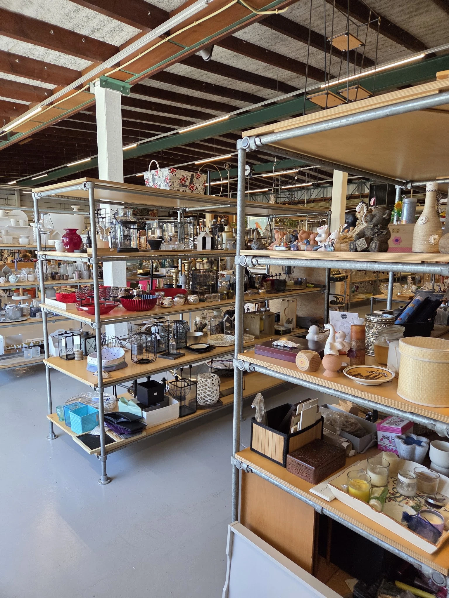 Metalen stellingen met diverse huishoudartikelen, decoratie en kringloopgoederen uitgestald