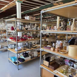 Metalen stellingen met diverse huishoudartikelen, decoratie en kringloopgoederen uitgestald