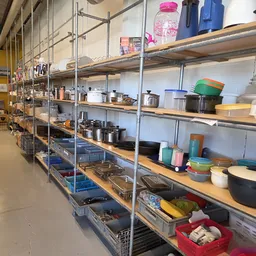 Metalen stellingen gevuld met diverse keukenartikelen, pannen, potjes en voedselcontainers