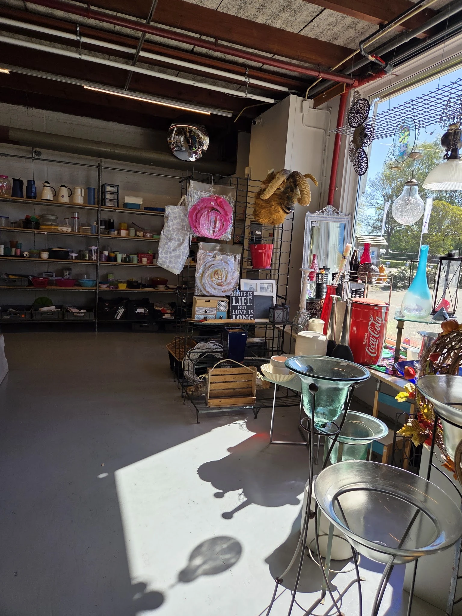 Winkelvloer van kringloopwinkel met stellingen, uitgestalde artikelen en diverse spullen