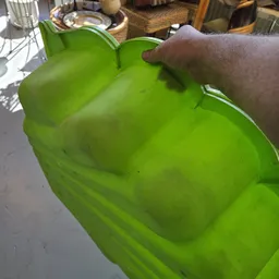 Groene plastic container of emmer, gedeeltelijk gevuld, vastgehouden door een hand
