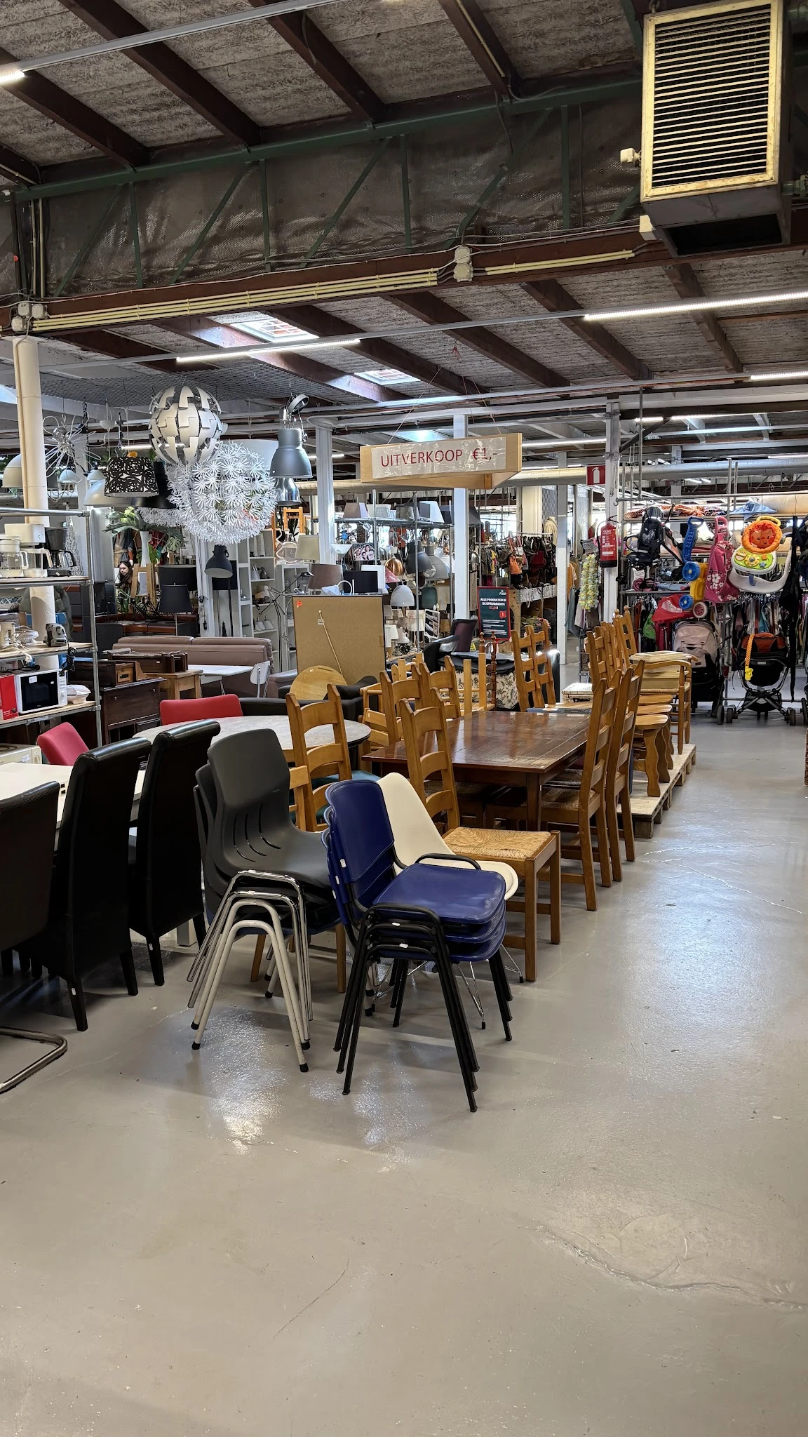 Winkelvloer met houten eettafels, stoelen in verschillende kleuren, en diverse artikelen op de achtergrond