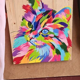 Kleurrijke pop-art schildering van een kat op hout, met fel gekleurde geometrische vlakken in roze, geel, blauw en groen