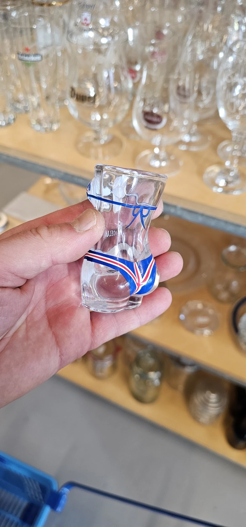 Glazen flesje met blauwe en rode lint in een hand