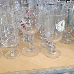 Verzameling glazen met logo's van verschillende merken op een houten tafel