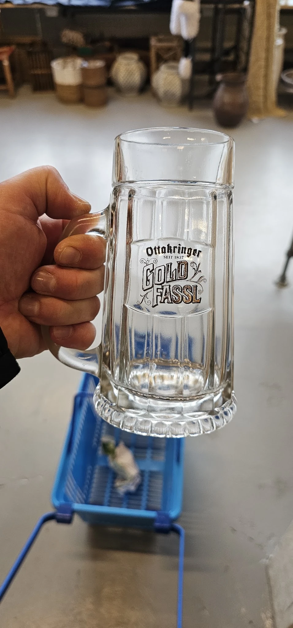 Glazen bierpul met opdruk 'Ottakringer Gold Fassl' wordt vastgehouden