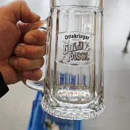 Glazen bierpul met opdruk 'Ottakringer Gold Fassl' wordt vastgehouden