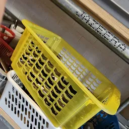 Gele plastic manden en witte stapelbare kratten in een kringloopwinkel