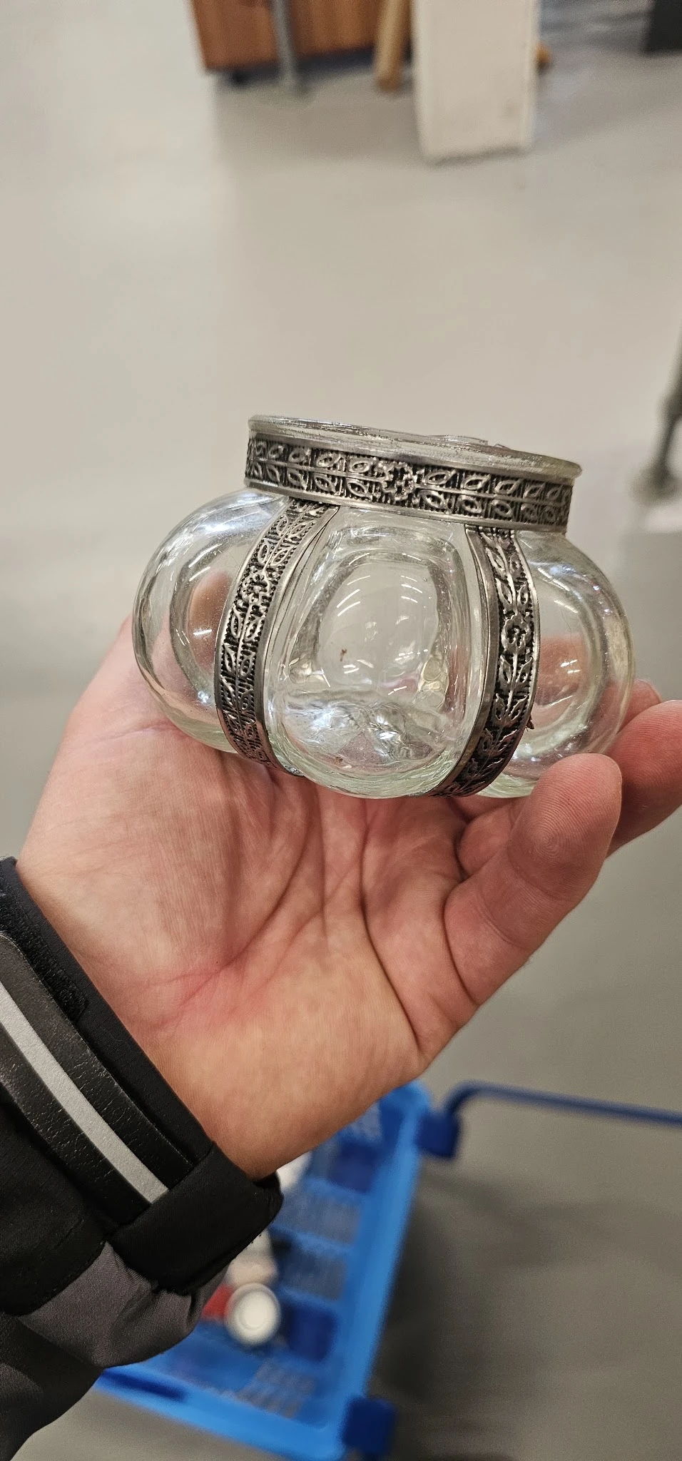 Close-up van een glazen potje met zilveren decoratieve band, gehouden in een hand