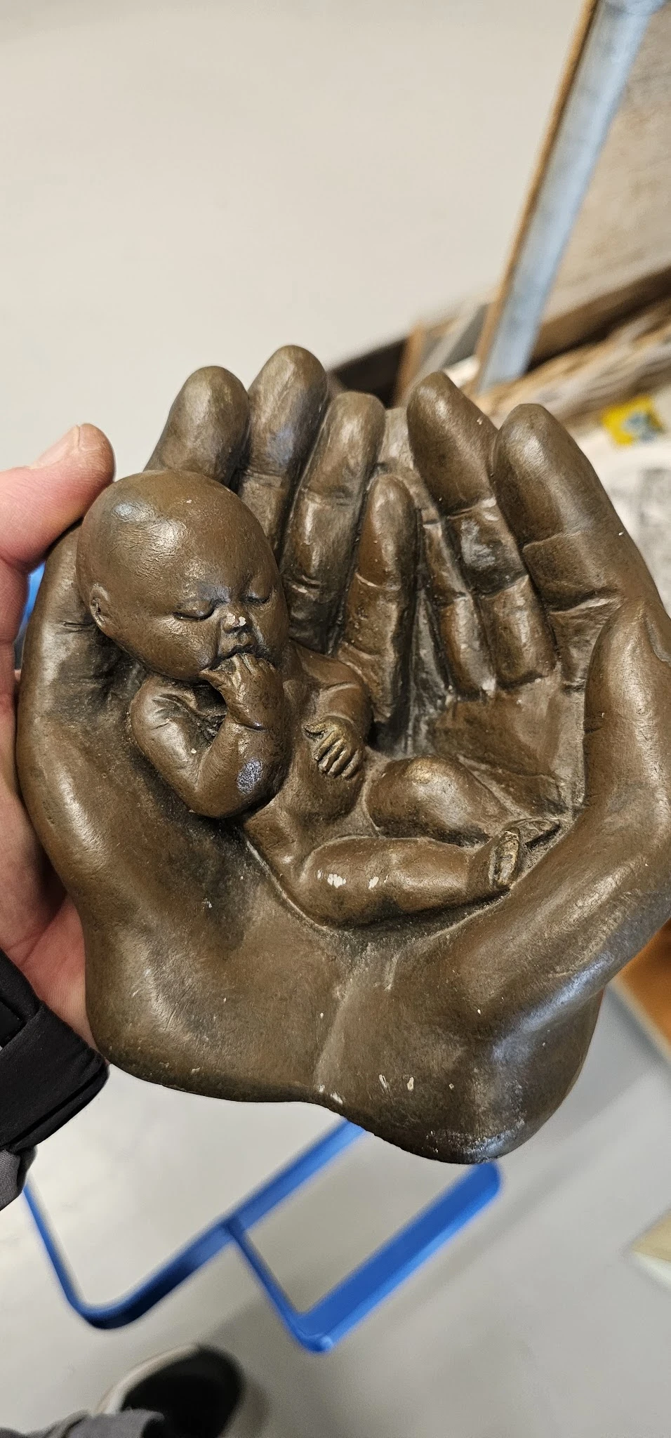 Bronzen beeldje van een baby in handen, close-up foto