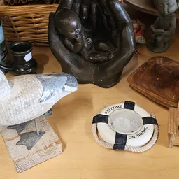 Diverse decoratieve artikelen op tafel: beeldhouwwerk, decoratieve vissen, lifebuoy-object en houten schaaltje
